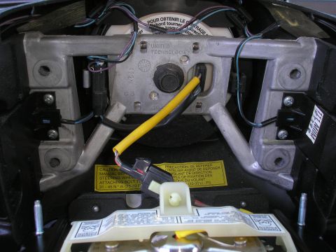 1995 Ford Bronco - Close-up view of the steering wheel's internal mechanism, showing wiring and caution labels.