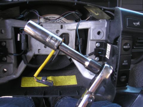 1995 Ford Bronco - Socket wrench is used to remove the steering wheel, with a yellow wire and warning label visible.