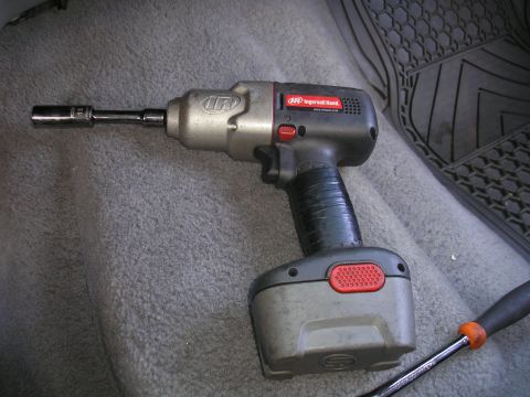1995 Ford Bronco - A close-up view of an Ingersoll Rand impact wrench and a socket, placed on the floor of a vehicle.