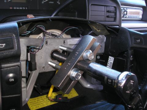 1995 Ford Bronco - Steering wheel removal tool in use on a vehicle's steering column.