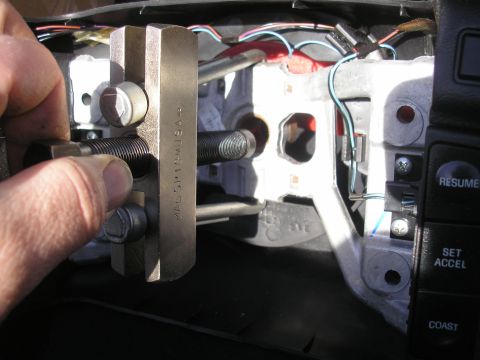 1995 Ford Bronco - Steering wheel removal tool in use on a vehicle's steering column, revealing internal wiring and components.