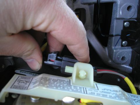 1995 Ford Bronco - A hand disconnects a wiring harness connector, likely for a steering wheel component.