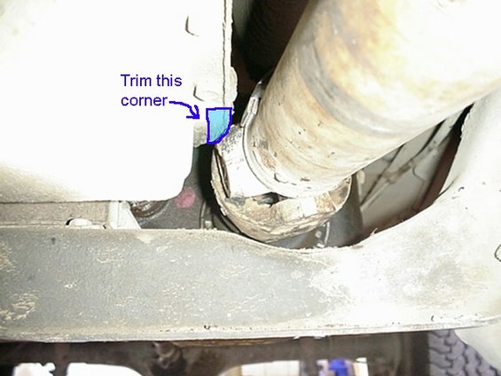 Close-up of a driveshaft U-joint and frame with a blue arrow indicating a corner to trim