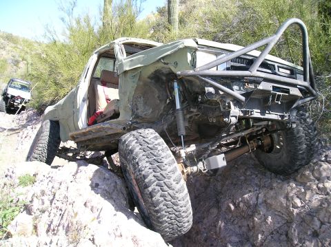 1986 Toyota Hilux - A heavily modified truck is stuck on a rocky trail with another vehicle visible in the background.