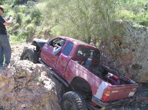 1986 Toyota Hilux - This Toyota pickup truck, likely from the early 2000s, is shown off-roading on a challenging rocky terrain.