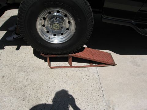 1986 Ford Bronco - A vehicle's tire is positioned on a red metal ramp, with a portion of the vehicle's body visible.