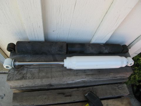 1986 Ford Bronco - Two shock absorbers are shown side-by-side on wooden planks against a white wall.