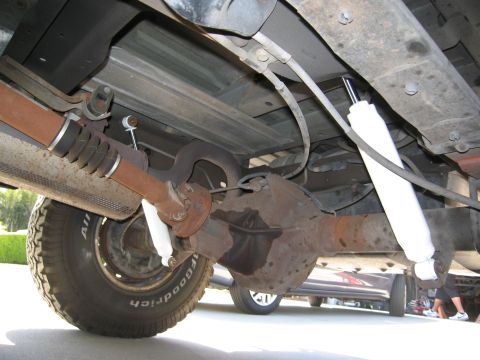 1986 Ford Bronco - The photo shows the rear axle and suspension components of a vehicle, with another car in the background.