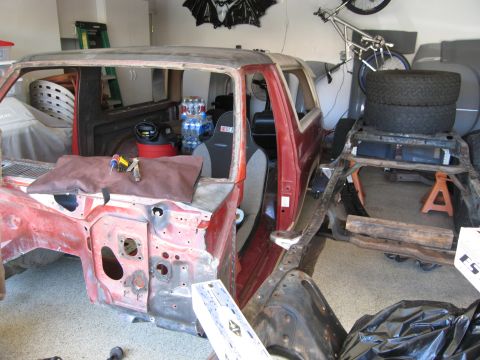 1986 Ford Bronco - This 1986 Ford Bronco body is undergoing restoration in a garage, showing its stripped-down interior and exterior.
