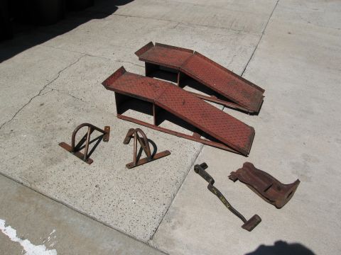 1986 Ford Bronco - A collection of automotive service parts, including ramps and wheel chocks, are laid out on a concrete surface.