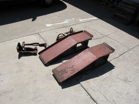 1986 Ford Bronco - A pair of car ramps and a vehicle suspension part are laid out on a cracked concrete driveway.