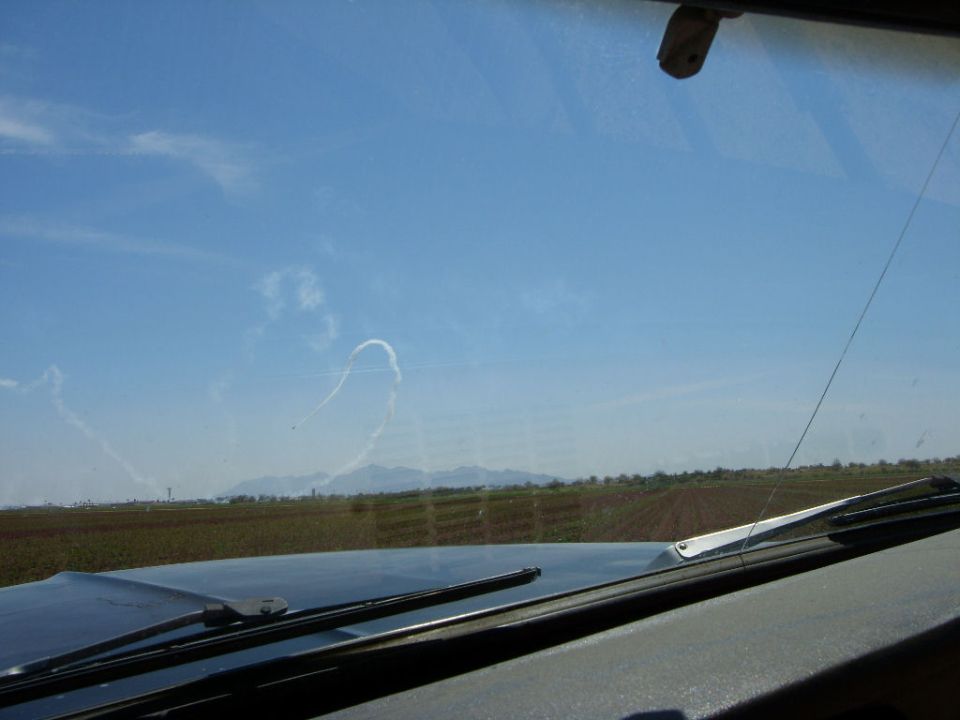 Interior view of vehicle looking out at sky with contrails and mountains