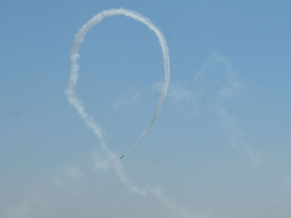 Plane makes a smoke loop in the sky. Supermotors.net logo at bottom right