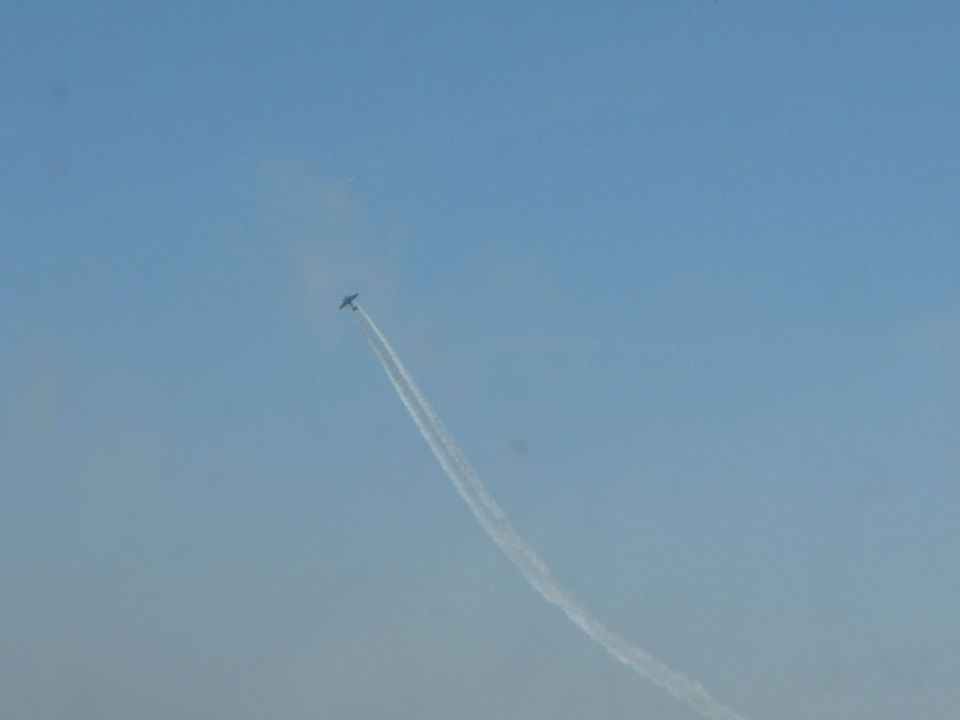 Airplane performing aerobatics with a smoke trail against a clear blue sky