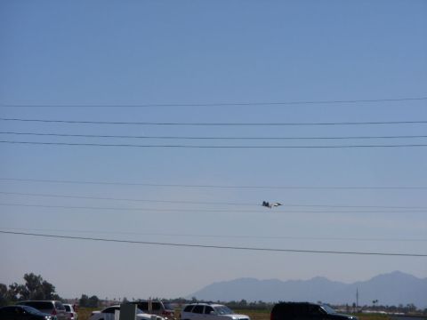1978 Ford Bronco - An airplane flies in the sky above a line of parked vehicles and power lines.