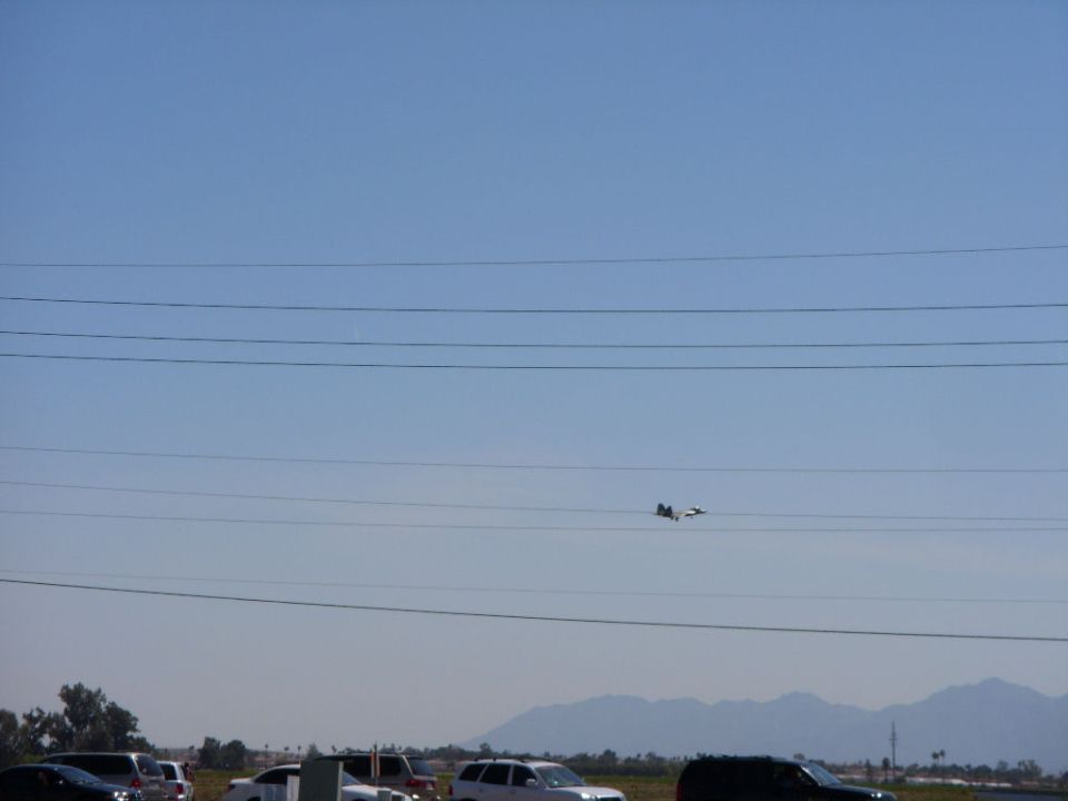 Airplane in flight over parked cars and utility lines