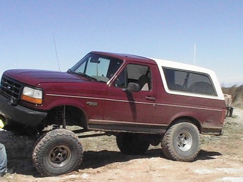 1992 Ford Bronco - This lifted 1992 Ford Bronco is shown in a three-quarter front view against a clear blue sky.