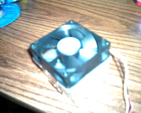 1990 Ford Taurus - A computer fan with attached wires rests on a wooden surface, with a blue CD nearby.