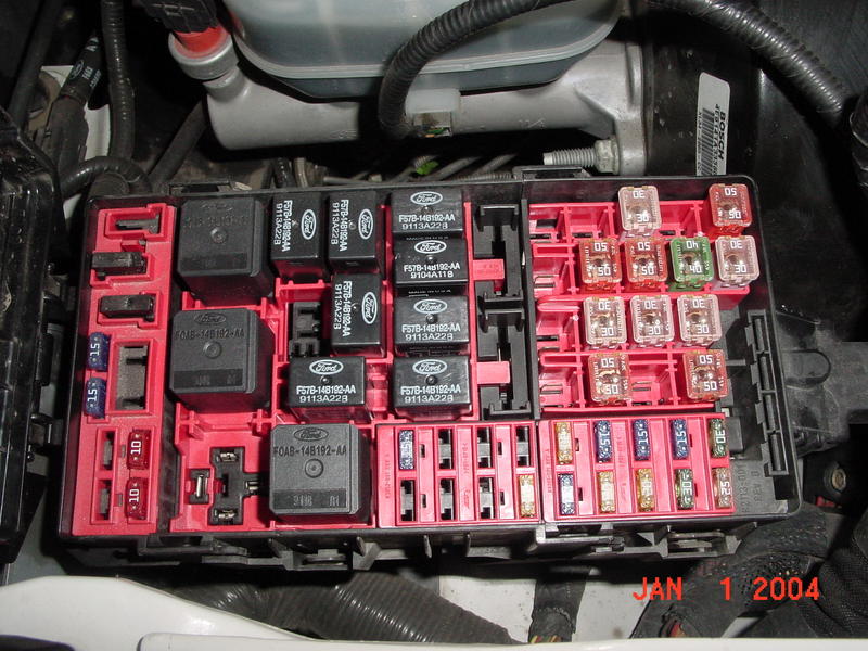 Close-up of a car's fuse box with various fuses and relays, some labeled with Ford