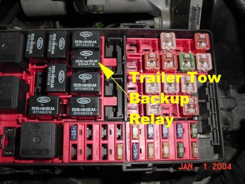 2007 Ford Mustang - Close-up of a vehicle's fuse box, showing various relays and fuses, with a yellow arrow pointing to the trailer tow backup relay.