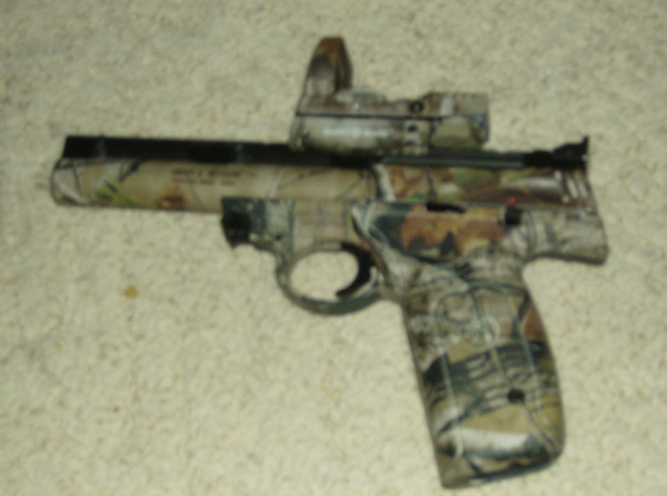 Camouflaged handgun with red dot sight on carpet