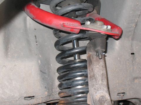 2001 Pontiac Trans Am - This photo shows a vehicle's front suspension, specifically a red control arm and coilover assembly.