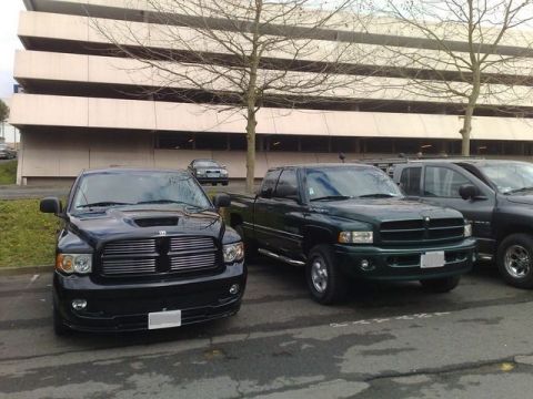 1991 Ford Crown Victoria - Two Dodge Ram pickup trucks are parked in front of a building.