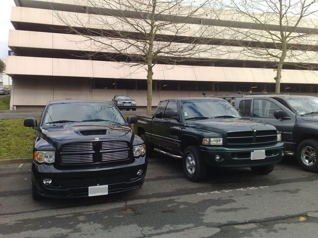 Front view of a black Dodge Ram pickup truck and a dark green Dodge Ram pickup truck parked side-by-side
