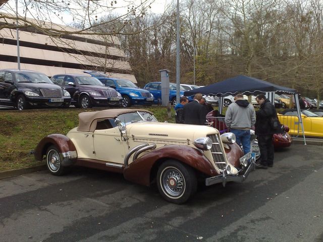 1930s Auburn convertible, cream and brown, with a tan soft top, parked outdoors
