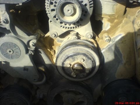 1992 Ford Crown Victoria - Close-up view of engine components, including pulleys and an alternator, covered in dust.