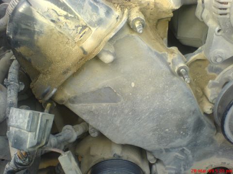 1992 Ford Crown Victoria - This image shows a close-up view of a dusty engine timing cover, highlighting mechanical components and wiring.