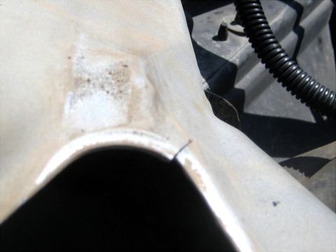 1996 Ford Bronco - Close-up looking down at a white fender lip above an aggressive-lug off-road tire, with chipped paint and dark rust bubbling in a patch of…
