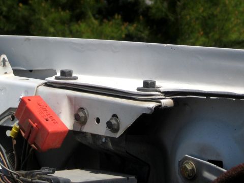 1996 Ford Bronco - Detail of a white inner fender and body-mount bracket with two large bolt heads through a shim stack, and a red plastic ANTI-LOCK TEST conn…