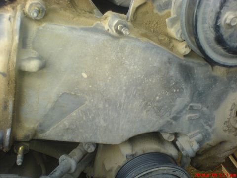 1992 Ford Crown Victoria - Close-up view of an engine timing cover, showing mechanical components and dust accumulation.