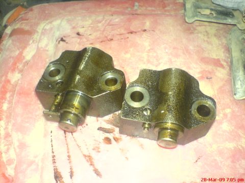 1992 Ford Crown Victoria - Two used timing chain tensioners are shown resting on a surface with oil stains.