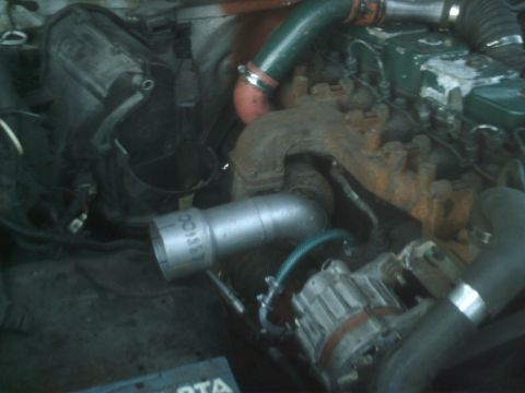 1989 Ford Bronco - Close-up view of an engine bay, focusing on the turbocharger and associated intake piping. Text is visible on one of the pipes.
