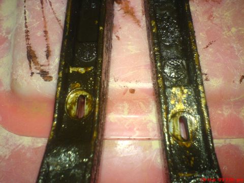 1992 Ford Crown Victoria - Close-up of two heavily soiled automotive timing chain guides, showing their worn condition and oily residue.