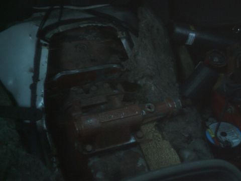 1989 Ford Bronco - Close-up of a red transmission part with visible bolts and housing.