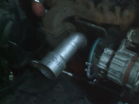 1989 Ford Bronco - Close-up view of engine components including an exhaust pipe, alternator, and manifold.