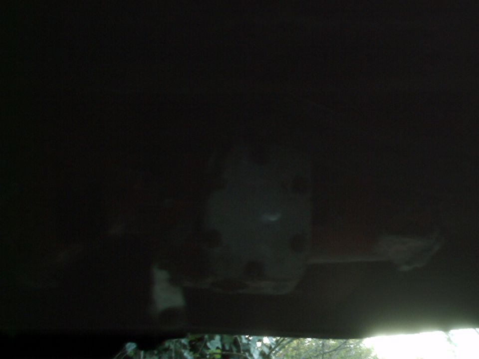 Underside of a dark-colored vehicle, showing a light-colored component with circular indentations