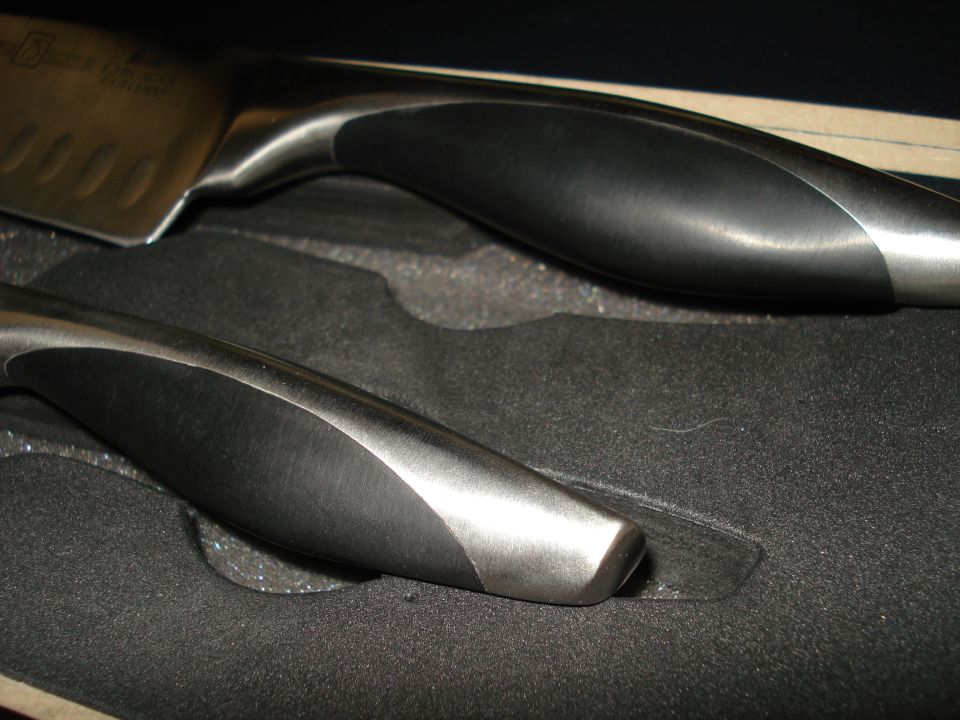 Close-up of two kitchen knife handles with black and brushed metal finish