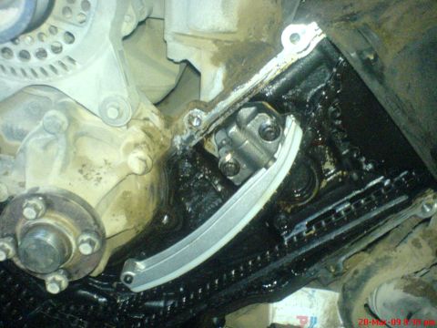 1992 Ford Crown Victoria - Close-up of an engine's timing chain and tensioner mechanism, showing oil buildup.