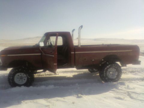 1992 Ford F-350 - A side view of a lifted red pickup truck with prominent exhaust pipes sits in a snowy landscape.