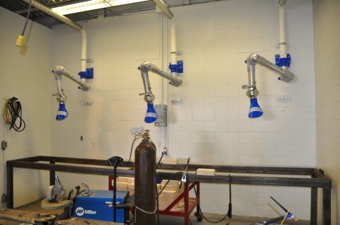 1996 Ford Bronco - A workshop area is equipped with three fume extraction arms and welding equipment, including a Miller welder and a gas cylinder.