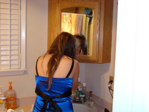 1989 Ford Bronco - A woman in a blue dress is at a bathroom sink, looking into a medicine cabinet mirror.