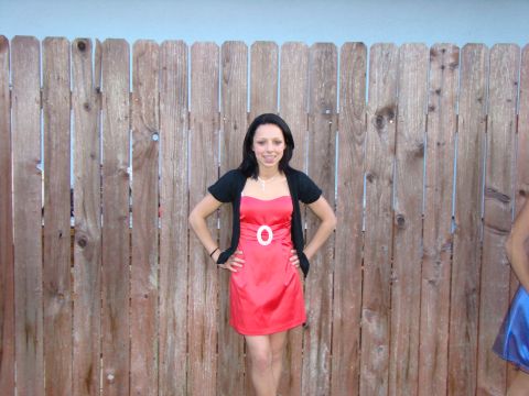 1989 Ford Bronco - A young woman poses for a photo in front of a rustic wooden fence, wearing a red dress and a black cardigan.