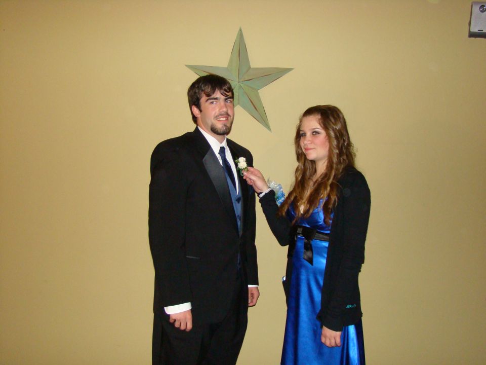 Man in tuxedo and woman in blue dress posing for a photo