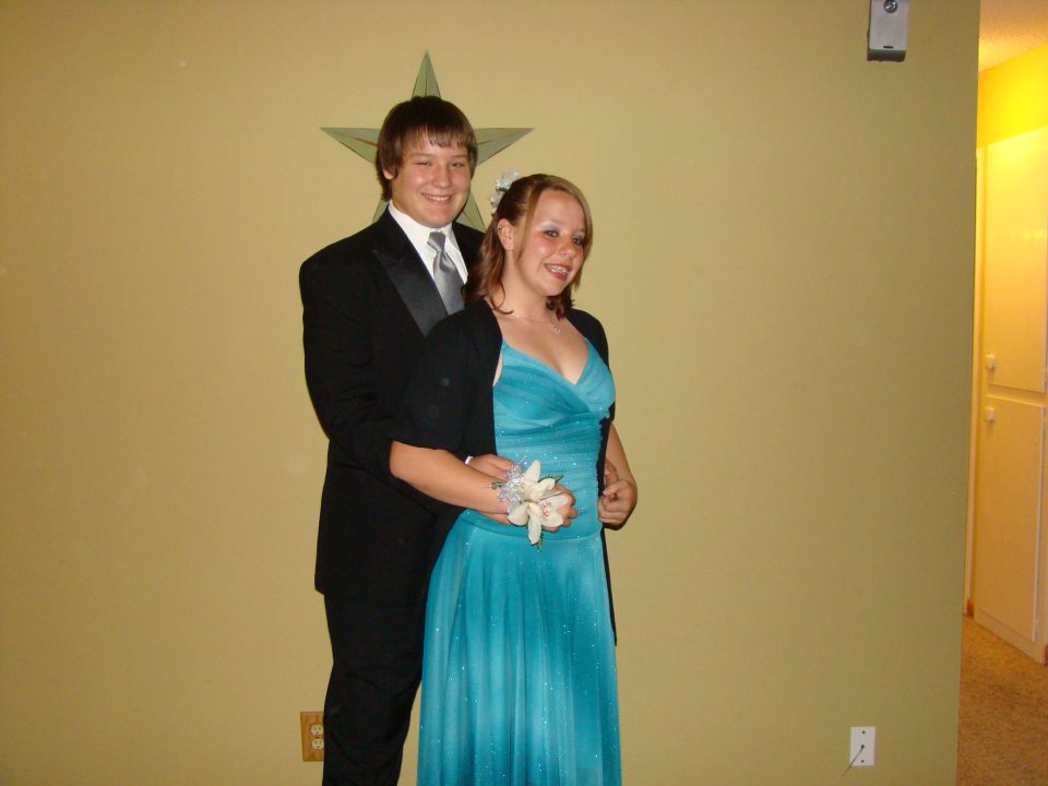 guy in tux and girl in blue dress posing for prom photo