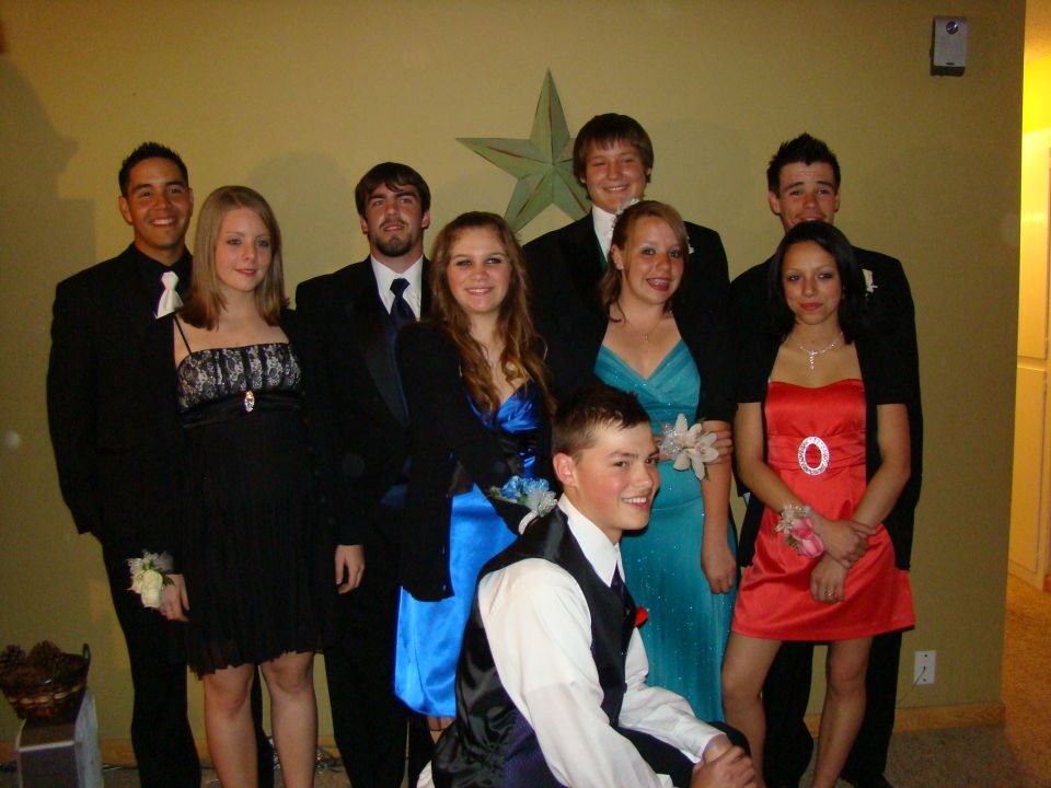 Group of ten young adults in formal wear posing for a photo indoors
