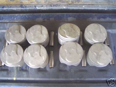 1972 Ford Ranchero - Set of eight pistons and wrist pins, likely for an engine rebuild or performance upgrade.